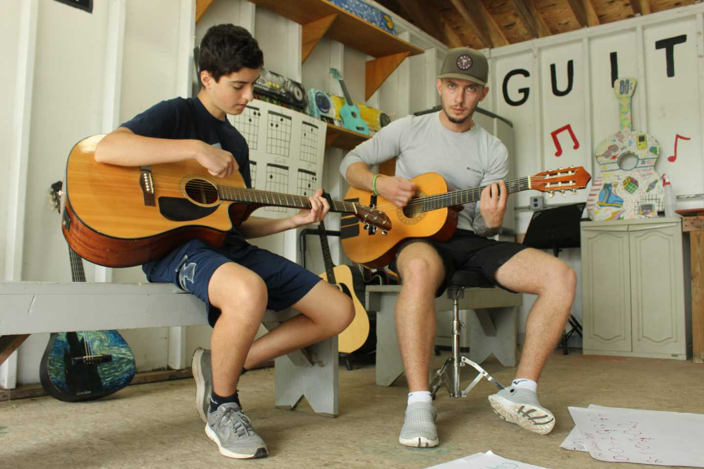 A camper learning how to play guitar.